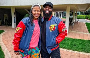 Couple wearing navy red vinyl outerwear garments outside capitol broadcasting company clothoo